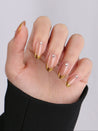 Hand with gold and clear nail polish on a plain background